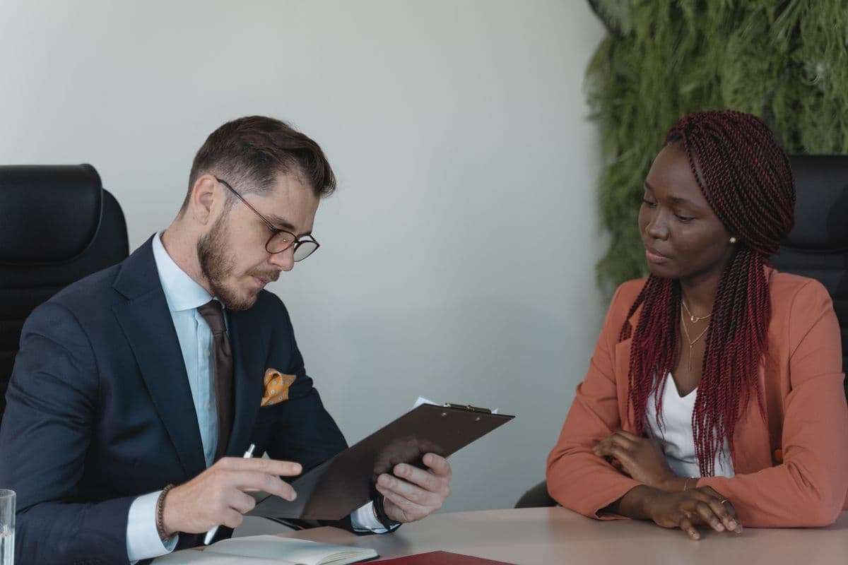 Woman in a job interview while the interviewer reads her CV on a clipboard