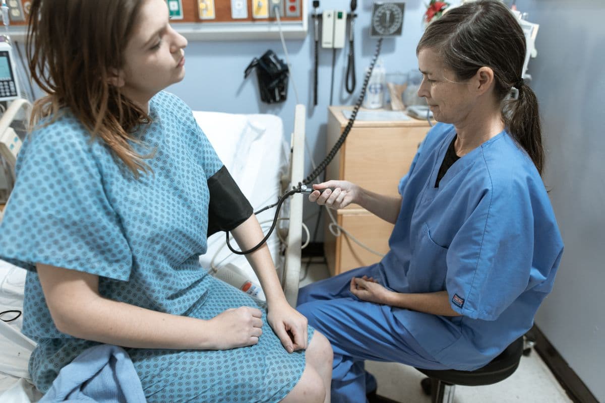Nurse sits beside a patient and checks her blood pressure with a cuff