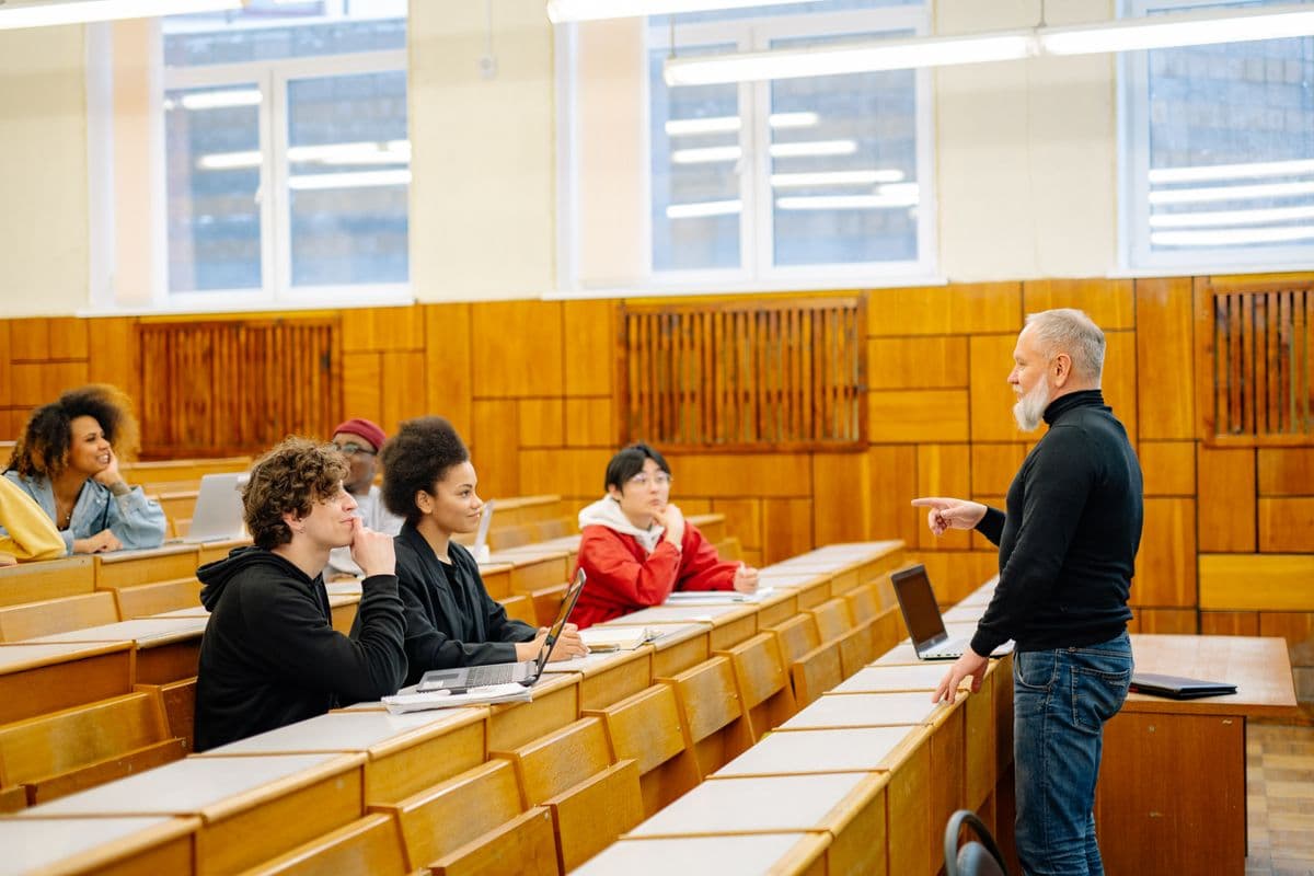 Students from different backgrounds listening to a lecturer in a wood-panelled university lecture hall